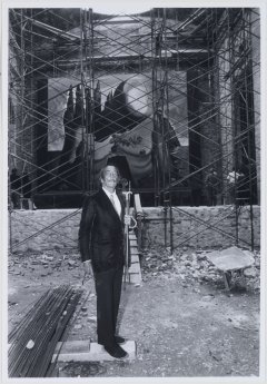 Picture of Salvador Dalí at the courtyard under construction of the Theatre-Museum in Figueres. There are some of the artist's works behind his figure